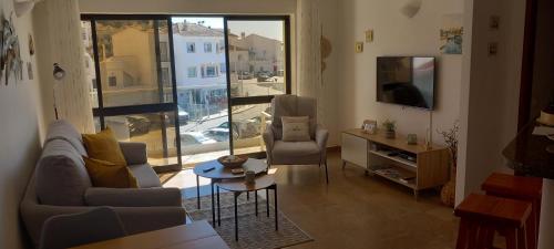 Una sala de estar con un sofá y sillas y una ventana. en Salema Beach Apartment, en Salema