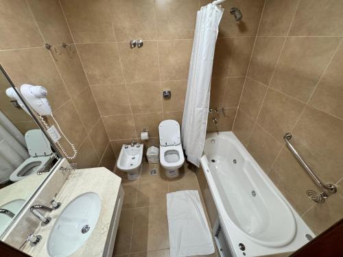 Un baño con lavabo, inodoro y bañera. en Atlantico Hotel, en Villa Gesell