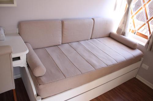 a couch in a room with a window at Center Suiço Flats in Campos do Jordão