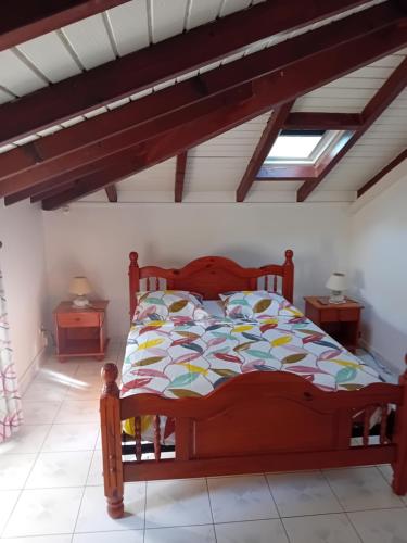 a bedroom with a wooden bed in a room at Haut de Villa LA FLEUR DE CANNE in Lamentin