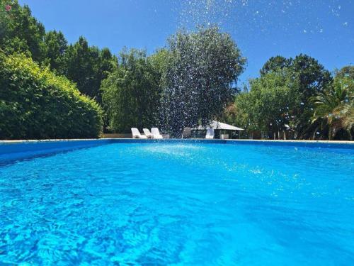 a swimming pool with two white chairs and trees at Cabañas Posada del Sol in Junín