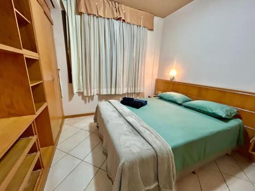 a bedroom with a green bed with a window at Vila da Serra,1min Biocor in Nova Lima