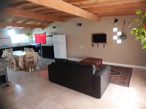 a living room with a black couch and a kitchen at La chacha in Colonia Chapadmalal