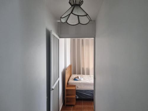 a hallway with a bedroom with a bed and a chandelier at Apartamento Centro Guarapari in Guarapari