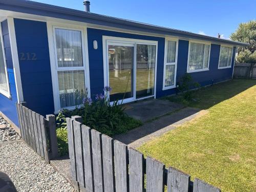 a blue house with a fence in front of it at Two One Two in Hokitika