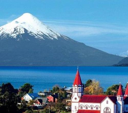 eine Stadt mit einem schneebedeckten Berg im Hintergrund in der Unterkunft Cabañas Volcanes del Sur, in Llanquihue