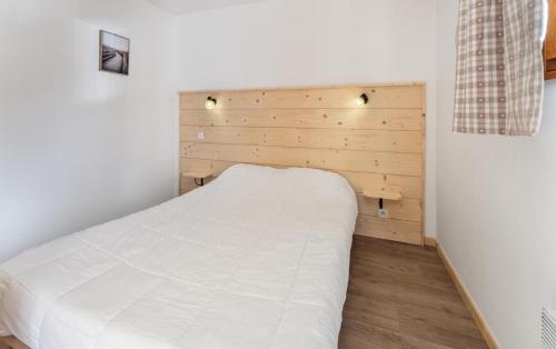 une chambre avec un lit blanc avec une tête de lit en bois dans l'établissement Résidence Les Hauts De Preclaux - Appartement rénové avec vue sur les pistes MAE-4431, aux Orres