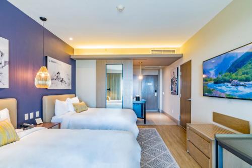 a hotel room with two beds and a tv at Torre Lucerna Hotel Ensenada in Ensenada