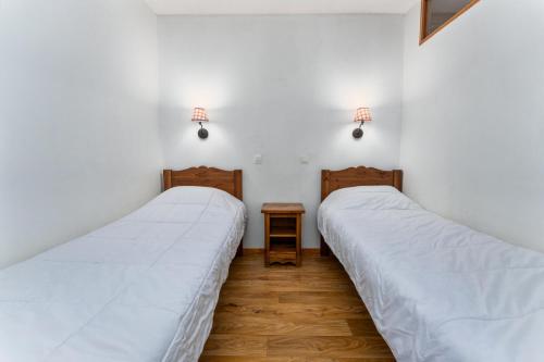 deux lits dans une chambre aux murs blancs dans l'établissement Résidence Les Hauts De Preclaux - Appartement 6 personnes aux Hauts de Préclaux MAE-2341, aux Orres
