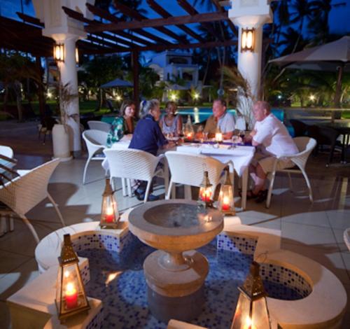 un grupo de personas sentadas alrededor de una mesa en un restaurante en Lantana Galu Beach, en Diani Beach