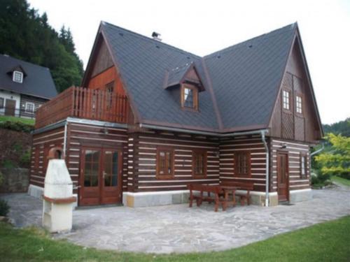 a large wooden cabin with a bench in front of it at Villa in Czechia with Heated Pool & Mountain Views in Vidochov