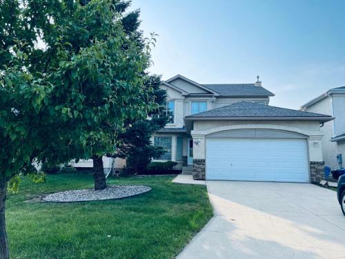 a house with a garage and a tree in the yard at Bedrooms in Kenaston, Close to Walmart, Costco, IKEA, Outlet, Unversity of Manitoba in Winnipeg