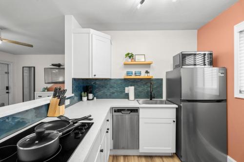 a kitchen with white cabinets and a stainless steel refrigerator at Boutique Beach Retreat in St Pete Beach
