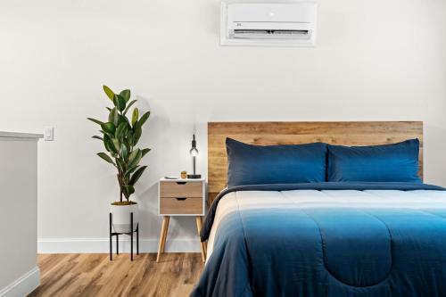 a white bedroom with a blue bed and a plant at Boutique Beach Retreat in St Pete Beach