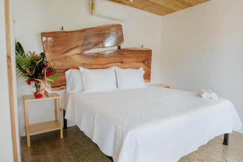 a bedroom with a white bed with a wooden headboard at Bonding Coffee Roaster Café & Hotel in Quepos