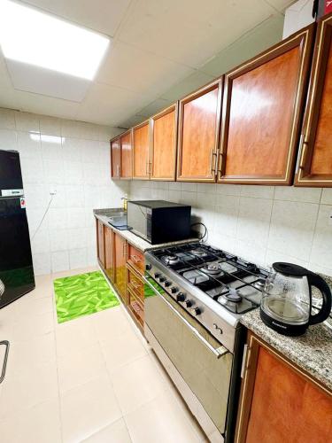 a kitchen with a stove and a green rug at Ajman Allegera Elegant Apartment Downtown in Ajman 