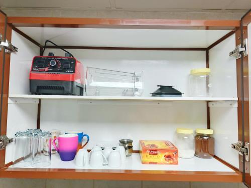 a shelf with cups and other items on it at Ajman Allegera Elegant Apartment Downtown in Ajman 