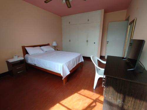 a bedroom with a bed and a desk and a television at Hotel Los Ebanos in Piura