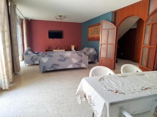 a bedroom with two beds and chairs and a television at Hotel Los Ebanos in Piura