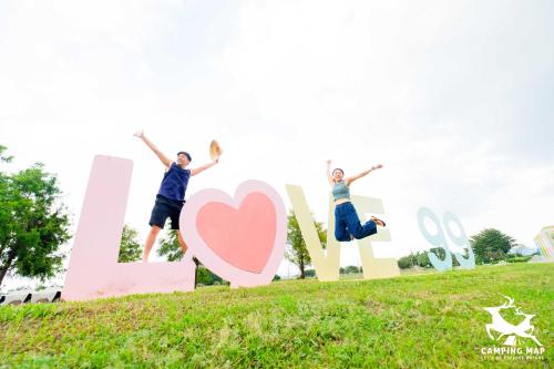 a group of people jumping in front of a sign at 99Glamping in Douliu