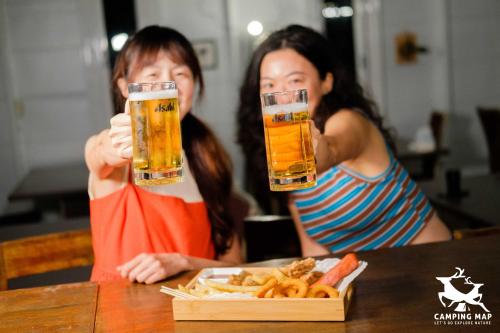 two girls sitting at a table with two glasses of beer at 99Glamping in Douliu