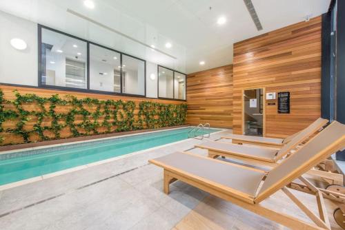 a pool with two lounge chairs next to a swimming pool at 180 Degrees Seaview and Harbor View 2 bedroom Apartment in Auckland