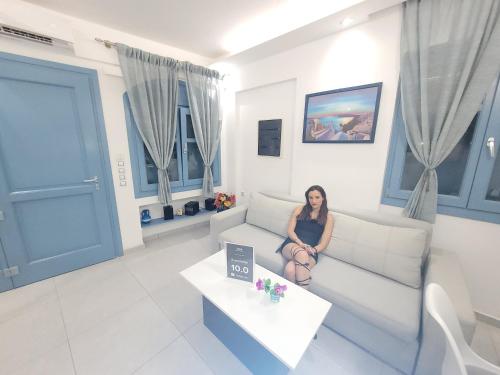 a woman sitting on a couch in a living room at Located by the sea one beachfront Private Captain Lazaros Pool Villa with loft in 750sqm spacious private plot-Jacuzzi-sunrelax-furnished terace-gazebo-private parking,sleep 3 adults and 2 children, just steps from the Black Beach-Seaview in Perissa