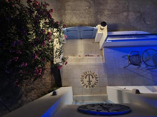 - prysznic na świeżym powietrzu z niebieskim oświetleniem w pokoju pełnym kwiatów w obiekcie Located by the sea one beachfront Private Captain Lazaros Pool Villa with loft in 750sqm spacious private plot-Jacuzzi-sunrelax-furnished terace-gazebo-private parking,sleep 3 adults and 2 children, just steps from the Black Beach-Seaview w mieście Perissa