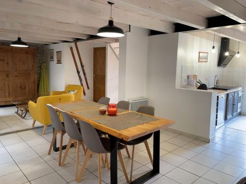 une cuisine et une salle à manger avec une table et des chaises en bois dans l'établissement Ancienne ferme rénovée avec jardin privé, poêle à bois et terrasse - FR-1-582-44, à Saint-Préjet-dʼAllier