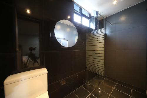 a bathroom with a toilet and a round mirror at Soho Hotel in Busan