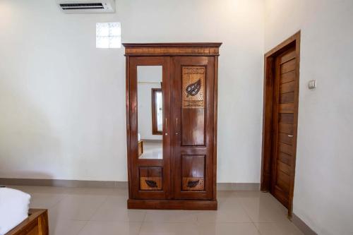 eine Holztür in einem Zimmer mit Spiegel in der Unterkunft Coconut Hill Cottage in Nusa Penida