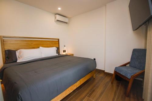 ein Schlafzimmer mit einem Bett und einem blauen Stuhl in der Unterkunft El Rincón de Casa Sara in La Loma