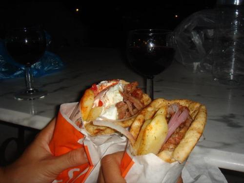 a person holding a sandwich with meat and cheese at Located by the sea one beachfront Private Captain Lazaros Pool Villa with loft in 750sqm spacious private plot-Jacuzzi-sunrelax-furnished terace-gazebo-private parking,sleep 3 adults and 2 children, just steps from the Black Beach-Seaview in Perissa