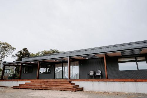 a black building with stairs in front of it at Forest Edge, The Catlins in Papatowai