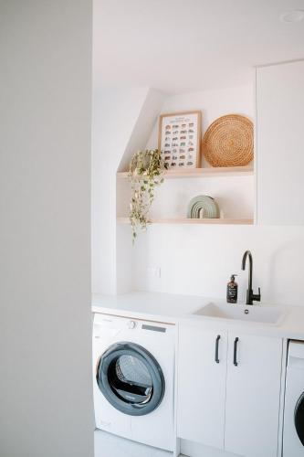 a white laundry room with a washer and dryer at Forest Edge, The Catlins in Papatowai