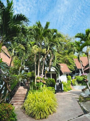 a garden with palm trees and stairs in front of a house at Tok Little Hut in Rayong