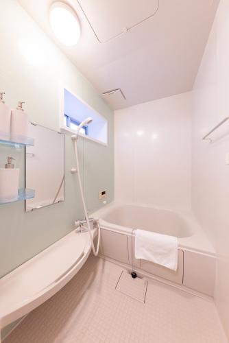 a white bathroom with a tub and a sink at Ritz Place Nishikujo in Osaka