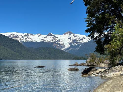 a view of a lake with snow covered mountains at Cabañas Alelí in Chaitén