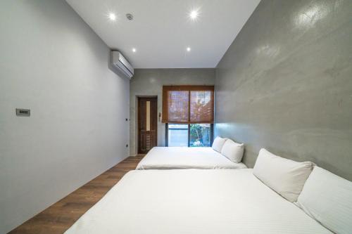 two beds in a room with two windows at Komorebi Souseki 樹沐漱石 安平民宿 in Tainan