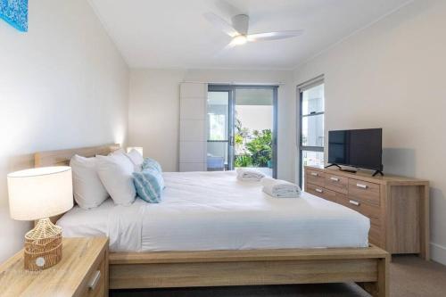a bedroom with a large bed and a television at Beaches Retreat - 3 BR w Pool - 5 Min to Beach in Agnes Water