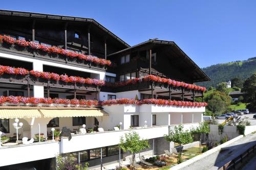 a white building with red flowers on the balconies at Hotel Serles in Mieders