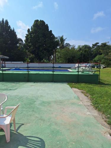 a tennis court with a fence and a swimming pool at Rancho Ohana in Peruíbe