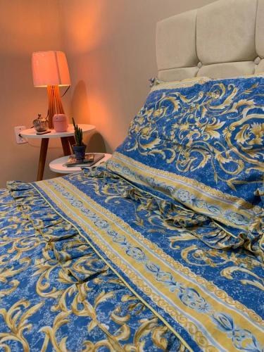 a bed with a blue and yellow blanket and a lamp at Quarto Privativo Suite Aérea in Aracaju