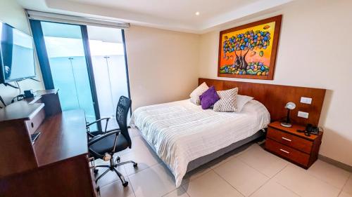 a bedroom with a bed and a desk with a chair at Departamento Frente al Mar en Manta Poseidon in Manta