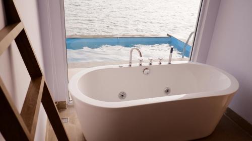 a white bath tub in a room with a window at One of A Kind Resort @Trikora Beach - Bintan in Telukdalam