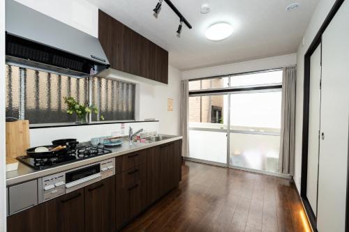 a kitchen with wooden cabinets and a large window at ohayo旅館 東矢口 in Tokyo