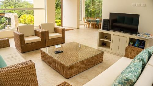 sala de estar con muebles de mimbre y TV en Moderna Casa-Paisajes Increíbles, en Anapoima