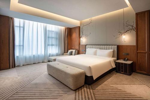 a bedroom with a large white bed and a couch at Howard Johnson by Wyndham Jufu Plaza Jinxi in Fuzhou