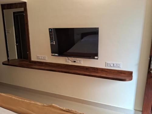 a flat screen tv on a wall in a room at Thavika Gold Mountain Wellness Resort in Tiruvannāmalai