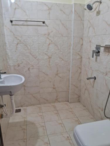 a bathroom with a shower and a sink and a toilet at Thavika Gold Mountain Wellness Resort in Tiruvannāmalai